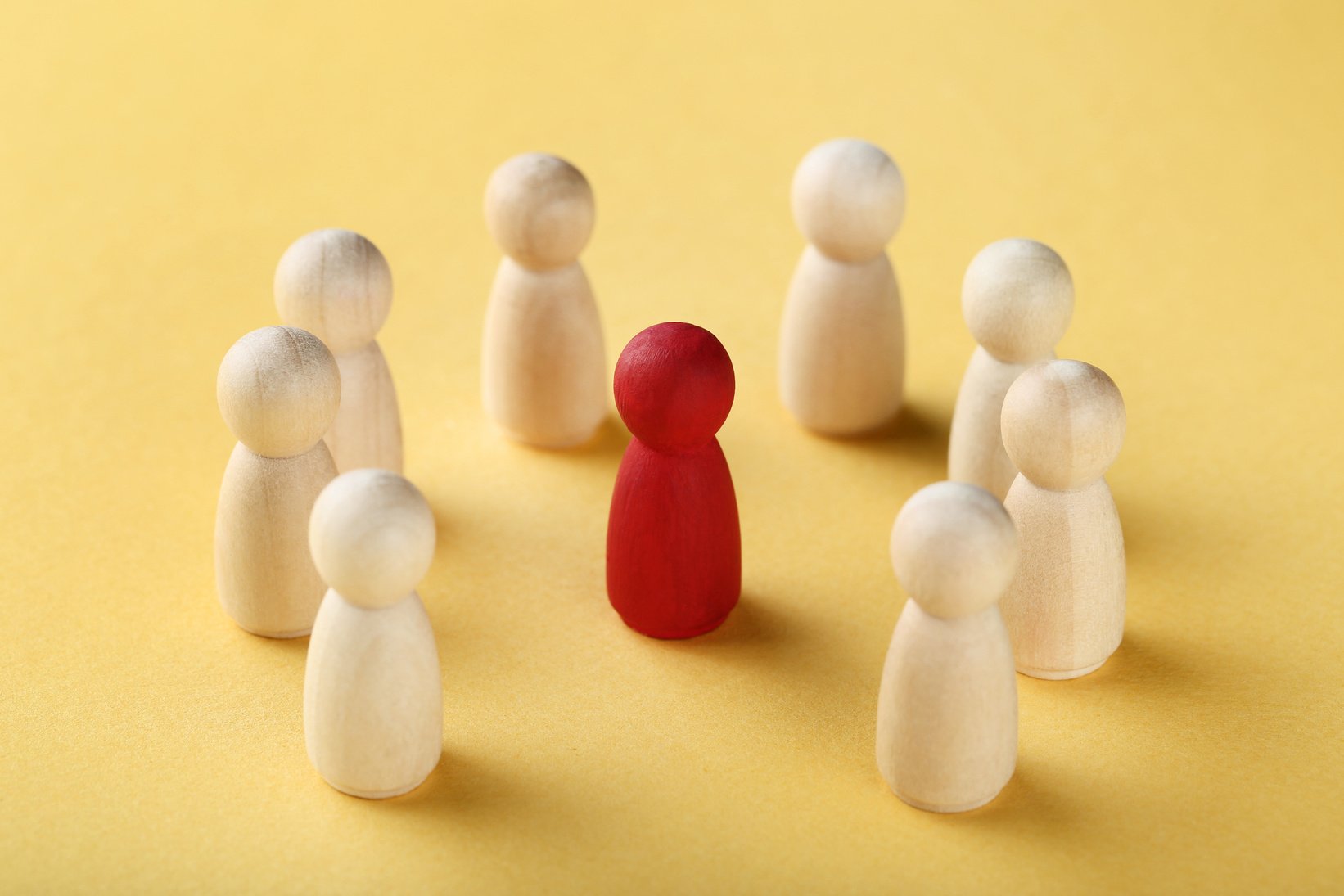 Leader concept. Wooden figures on yellow background